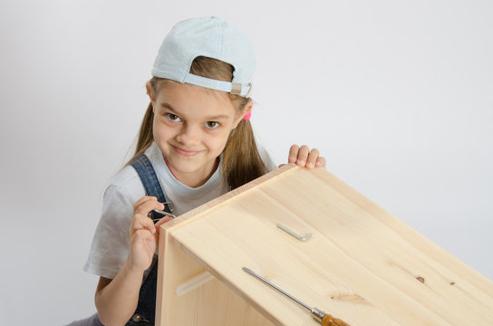 Little girl in image collector of furniture turn screw