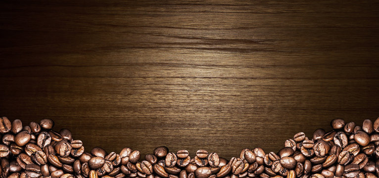 Coffee cup and coffee beans on a wooden table. Dark background © Tabthipwatthana