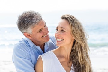 Fototapeta premium Happy couple smiling at each other by the sea