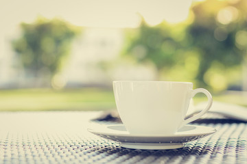 Coffee cup with book on blurred green nature background
