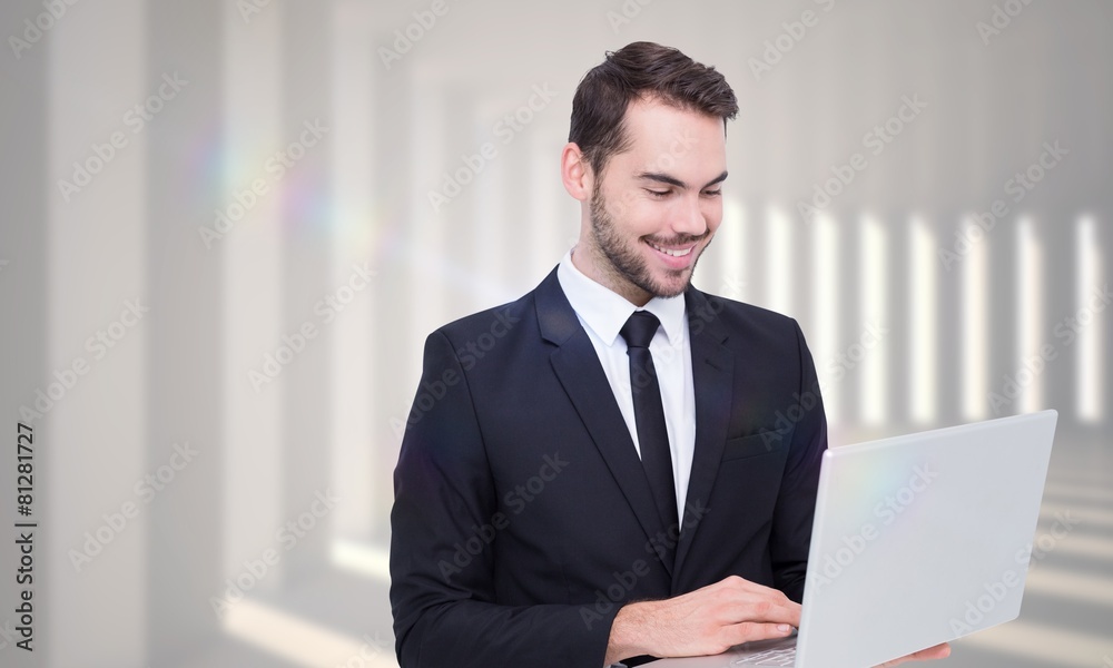 Poster composite image of smiling businessman standing and using laptop