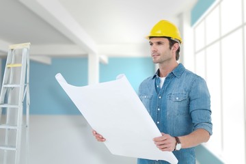 Composite image of architect holding blueprint in house