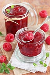 Homemade delicious raspberry jam on a rustic wooden table
