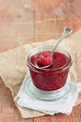 Homemade delicious raspberry jam on a rustic wooden table