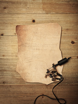 Piece of leather and tattoo machine on vintage wood desk