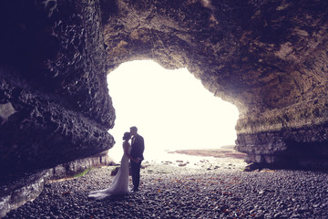 Bride and groom in a cave near ocean