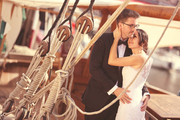 Bride and groom embracing near big ship with strings
