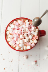 Hot chocolate with marshmallows in red cup on table