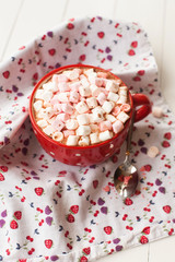 Hot chocolate with marshmallows in red cup on table