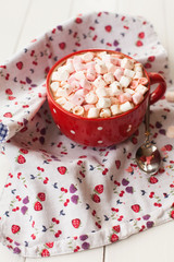 Hot chocolate with marshmallows in red cup on table