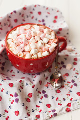 Hot chocolate with marshmallows in red cup on table
