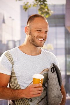 Happy man walking on street holding coffee