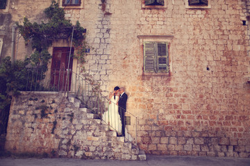 Fototapeta na wymiar Bride and groom on stairs near a house