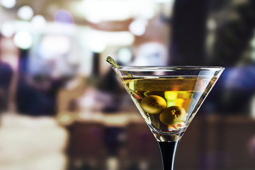 glass with martini and green olives