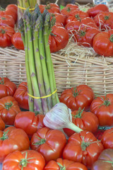 Asparagus, tomatoes, and garlic on display on a market stall