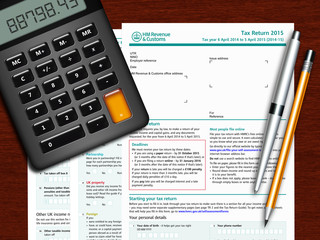 SA100 tax return form with calculator and pencil on wooden table