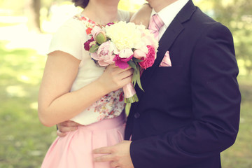 Obraz na płótnie Canvas Bride holding beautiful bouquet, embracing her groom
