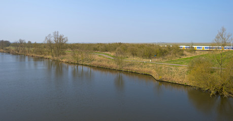 Train driving along a canal in spring