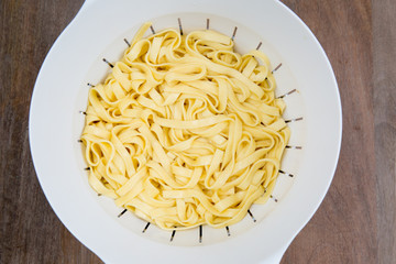 Freshly made fettucini pasta in a collander