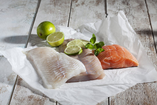 Fischfilet, Schellfisch, Seelachs, Lachs, Limetten, auf Papier