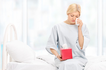 Sad female patient crying seated on a hospital bed