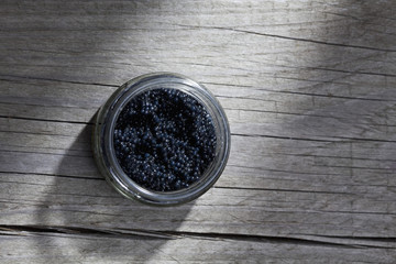Schwarzer Kaviar im Gläschen auf Holz