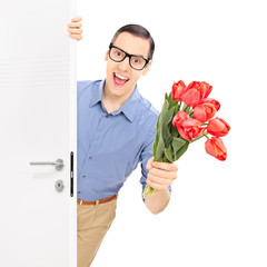 Man entering a room with bunch of red tulips
