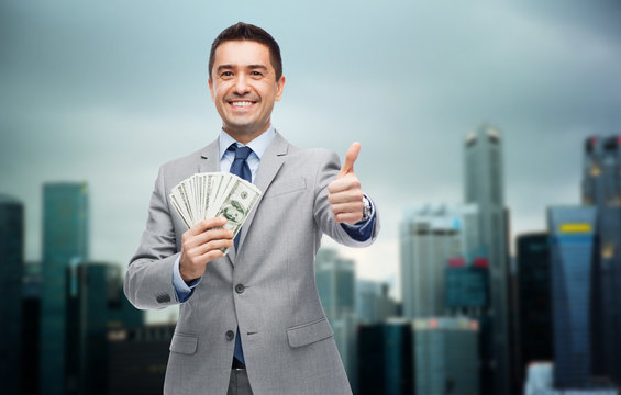 Smiling Businessman With Money Showing Thumbs Up