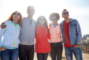 happy teenage friends in shades hugging on street