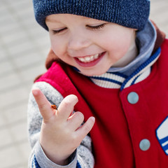 Toddler smiling child looking at a ladybug