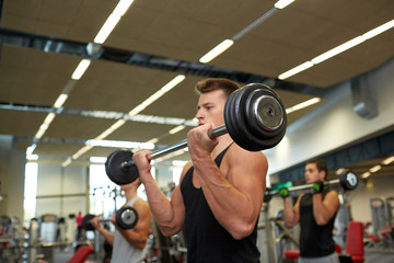 Fototapeta na wymiar young men flexing muscles with barbells in gym