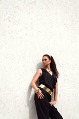 Woman in black suit with golden waistband posing on white backgr