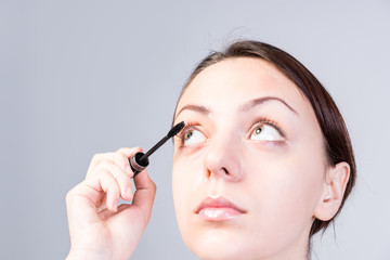 Woman Putting Mascara on Lashes While Looking Up