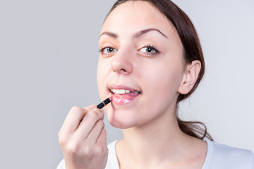 Woman Applying Lipstick While Looking at Camera
