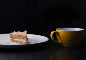 Cake on round white plate and yellow cup