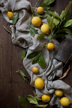 group of fresh lemons with leaves on wooden table with grater