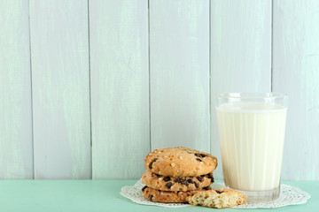 Tasty cookies and glass of milk on color wooden background