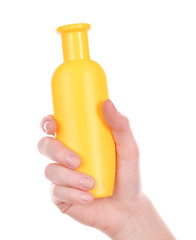 Bottle of suntan cream in female hand isolated on white