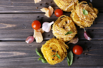 Raw pasta with cheese and vegetables on wooden background