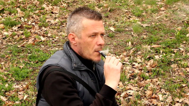 handsome man vaping e cigarette outdoor in the field