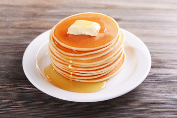 Delicious pancakes with honey on plate on table close-up