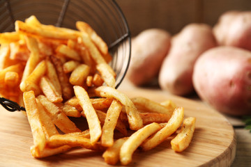 Tasty french fries in metal basket on wooden table background