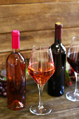 Bottles and glasses of wine with grape on wooden background