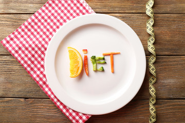 Word DIET made of sliced vegetables in plate with measuring