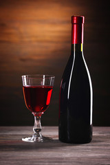 Wineglass and bottle on wooden background