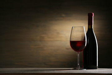 Wineglass and bottle on wooden background