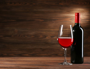 Wineglass and bottle on wooden background