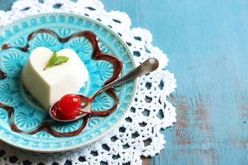 Tasty panna cotta dessert on plate, on wooden table