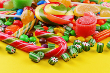Colorful candies on yellow background