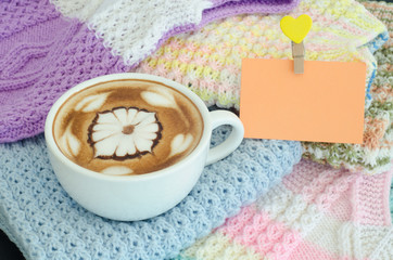 A cup of latte art on a knitted vest background